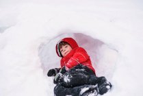 Ritratto ravvicinato di Boy sdraiato in un buco nella neve — Foto stock