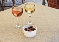 Glasses of white and rose wine with a dish of olives — Stock Photo