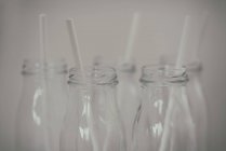 Вид крупним планом П'ять скляних пляшок з питними соломинками — стокове фото