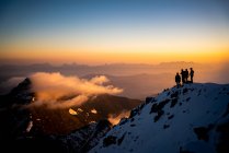 Group of people on mountains peak with sunset sky — Stock Photo