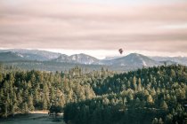 Heißluftballon fliegt über Berglandschaft, South Dakota, Amerika, USA — Stockfoto