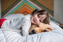 Chica joven jugando con el perro en una cama - foto de stock