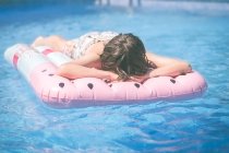 Menino deitado em uma cama de ar inflável em uma piscina — Fotografia de Stock