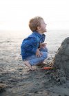 Счастливый мальчик строит песчаный замок на пляже, Округ Ориндж, Калифорния, США — стоковое фото