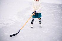 Girl playing ice hockey on frozen lake — Stock Photo