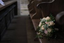 Ramo de rosas en un banco en una iglesia - foto de stock