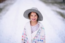 Junges Mädchen mit Hut draußen in eine Decke gehüllt — Stockfoto