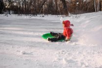 Boy sledging in the snow on winter day — Stock Photo