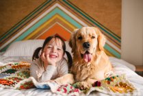 Молода дівчина грає з собакою на ліжку — стокове фото