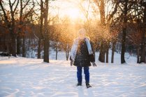 Хлопчик стоїть в лісі кидає сніг в повітрі — стокове фото
