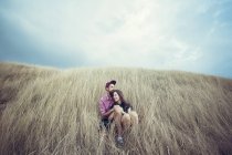 Пара сидящих в поле обнимающих — стоковое фото