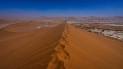 Vista lejana de Man walking along ridge of a sand dune, Deadvlei near Sossusvlei, Namib Naukluft National Park, Namibia - foto de stock