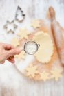 Обрезанное изображение женской руки, посыпающей муку на тесто для рождественского печенья — стоковое фото