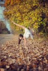 Girl standing upside down in autumn leaves doing yoga — Stock Photo