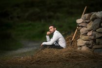 Farmer sitting on a pile of hay, Ireland — Stock Photo