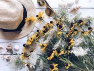 Wildflowers, straw hat, sunglasses and seashells — Stock Photo