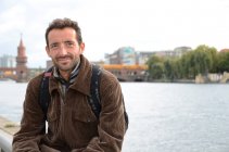 Портрет мужчины, сидящего перед мостом Обербаум, Берлин, Германия — стоковое фото