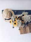 Buquê de flores em uma cesta pendurada em um rack de casaco com um chapéu — Fotografia de Stock