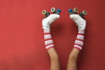 Pernas de menina vestindo meias longas e patins de cabeça para baixo contra uma parede — Fotografia de Stock