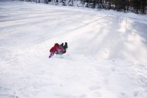 Хлопчик катається на санях у снігу взимку — стокове фото