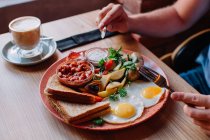 Imagem cortada de mulher comendo um ovo e bacon café da manhã — Fotografia de Stock