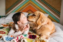Молодая девушка играет с собакой на кровати — стоковое фото