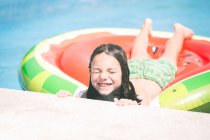 Garçon souriant sur un lit gonflable de pastèque dans une piscine — Photo de stock
