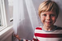 Портрет мальчика с веснушками, стоящего у окна — стоковое фото