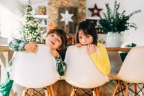 Menino e menina sentados na mesa de jantar brincando no Natal — Fotografia de Stock