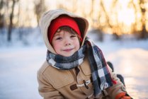 Портрет улыбающегося мальчика, сидящего на замерзшем озере — стоковое фото