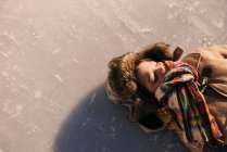Boy lying on a frozen lake on nature — Stock Photo