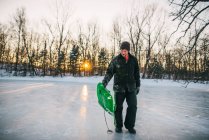 Uomo in piedi su un lago ghiacciato con in mano una slitta — Foto stock