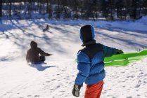 Хлопчик катається зі своєю матір'ю на зимовому снігу — стокове фото