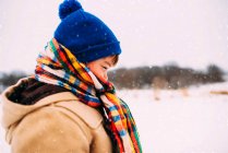 Портрет мальчика, стоящего в снегу, завернутого в шляпу и шарф — стоковое фото