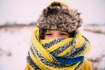 Ritratto di una ragazza in piedi sulla neve avvolta in un cappello e una sciarpa — Foto stock