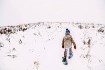 Garçon marchant dans la neige portant des raquettes — Photo de stock