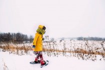 Menina andando na neve usando sapatos de neve — Fotografia de Stock