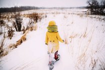 Chica caminando en la nieve usando raquetas de nieve - foto de stock