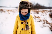 Retrato de una niña de pie en la nieve envuelta en un sombrero y una bufanda - foto de stock