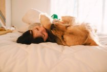 Menina deitada em uma cama com seu cão golden retriever — Fotografia de Stock