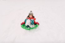Молода дівчина катається на санях у важкому снігу — стокове фото