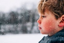 Retrato de un niño parado en la nieve - foto de stock
