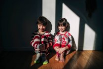 Junge und Mädchen im Schlafanzug sitzen im Sonnenlicht auf dem Fußboden — Stockfoto
