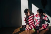 Menino e menina sentados no chão abraçando — Fotografia de Stock