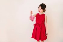 Menina sorridente segurando uma decoração de forma de coração — Fotografia de Stock