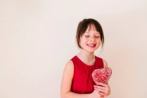 Menina sorridente segurando uma decoração de forma de coração — Fotografia de Stock
