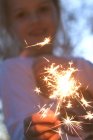 Sorrindo menina segurando um sparkler — Fotografia de Stock