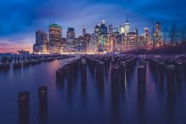 Ciudad skyline por la noche visto desde Brooklyn Bridge Park, Manhattan, Nueva York, América, EE.UU. - foto de stock
