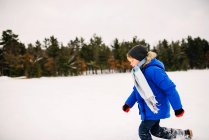 Мальчик бежит в снегу по замерзшему озеру — стоковое фото