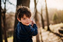 Хлопчик грає на мотузці в лісі — стокове фото